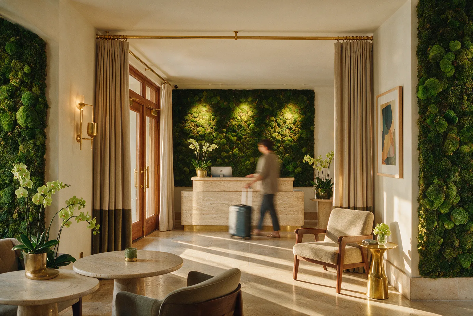 Lobby de hotel boutique con mostrador de travertino y un gran muro de musgo preservado iluminado