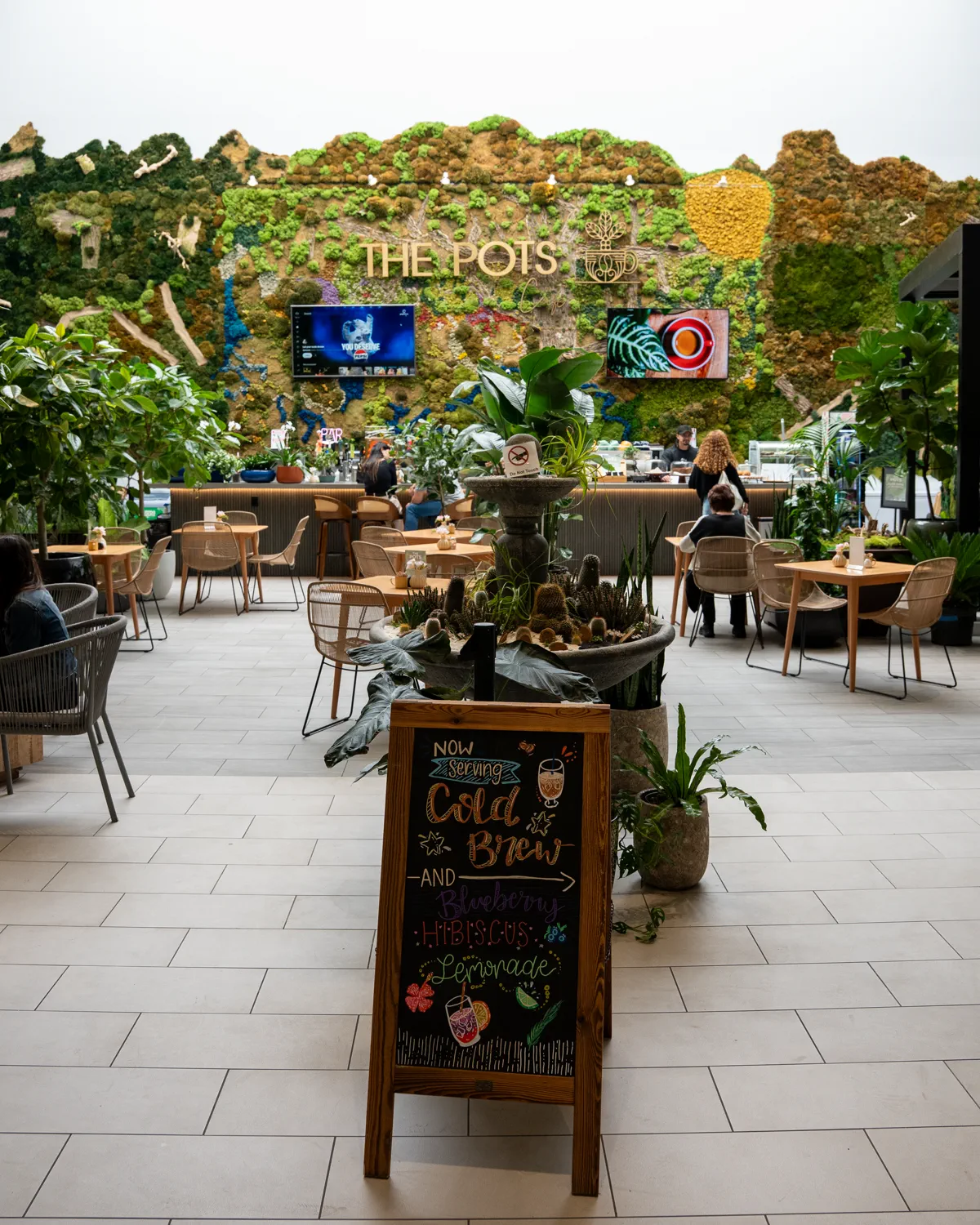 Interior de The Pots Cafe con la pared de musgo