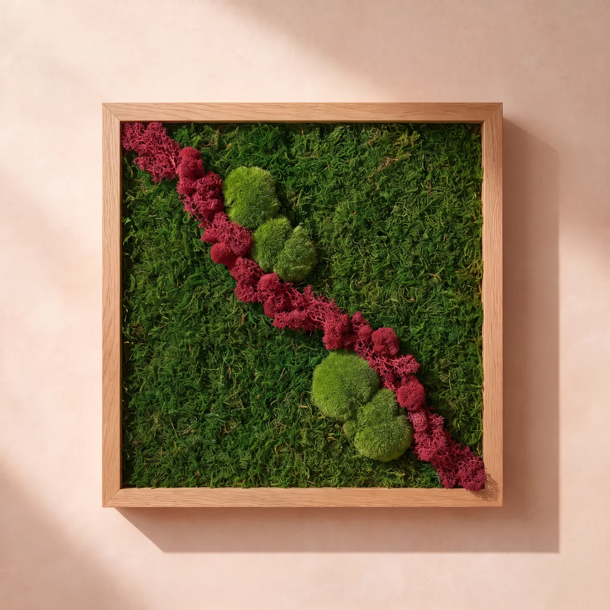 Una composición en tonos rojos y burdeos con texturas de musgo y liquen preservados, en un marco cuadrado de roble claro.