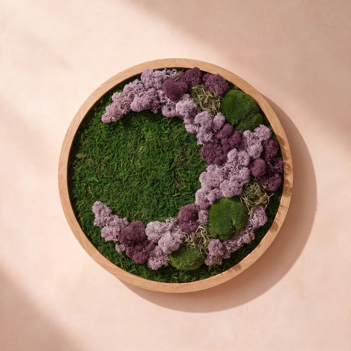 Una composición en tonos lilas con texturas de musgo y liquen preservados, en un marco redondo de roble claro.