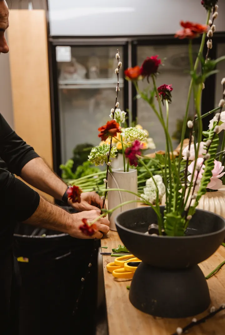 Un ikebana en clase. Montando un ikebana de flor roja en un cuenco negro.