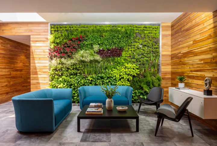 Un lounge con muro vivo. Jardín vertical de suelo a techo junto a la madera.