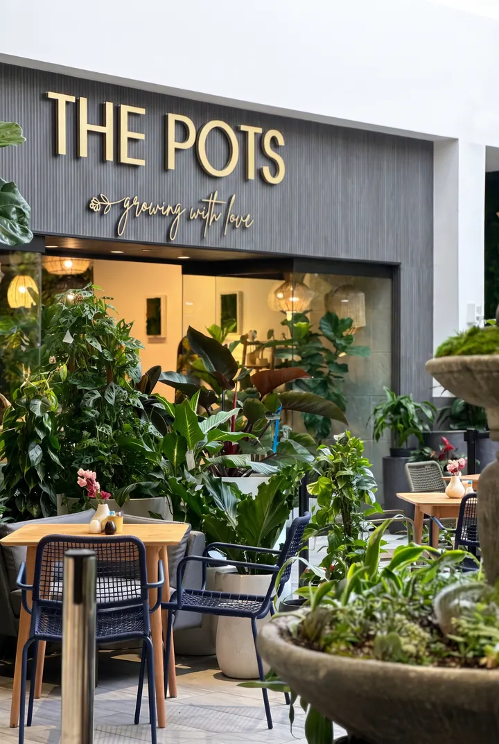 La entrada del café. Plantas, mesas y el letrero de The Pots a la puerta.
