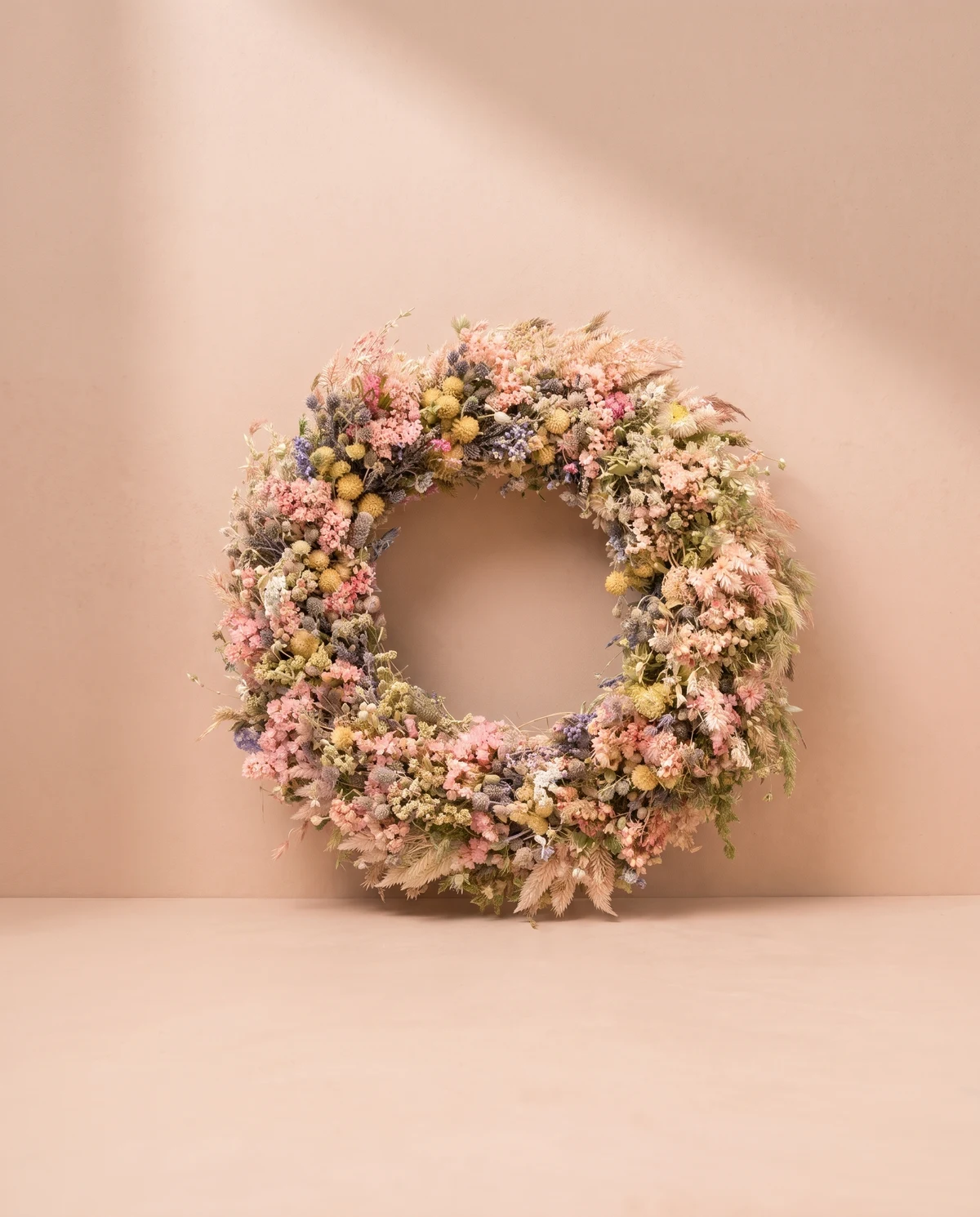 Flores y pequeños elementos botánicos preservados en una corona de tonos suaves.